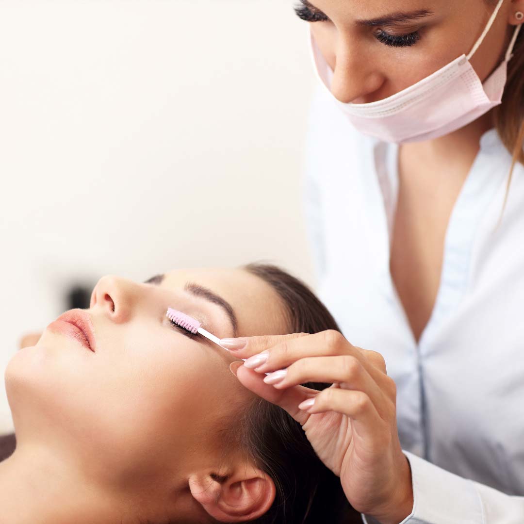 Eyelash technician brushing client's eyelashes