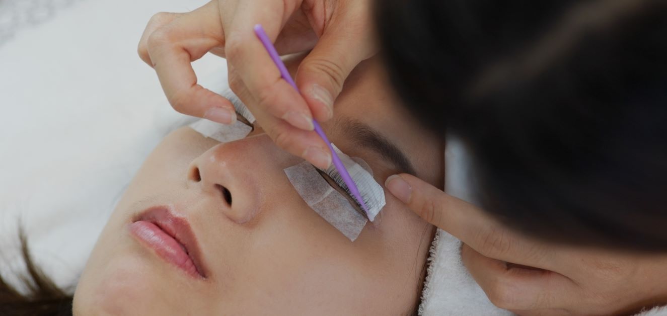 lash tech lifting a woman's eyelashs