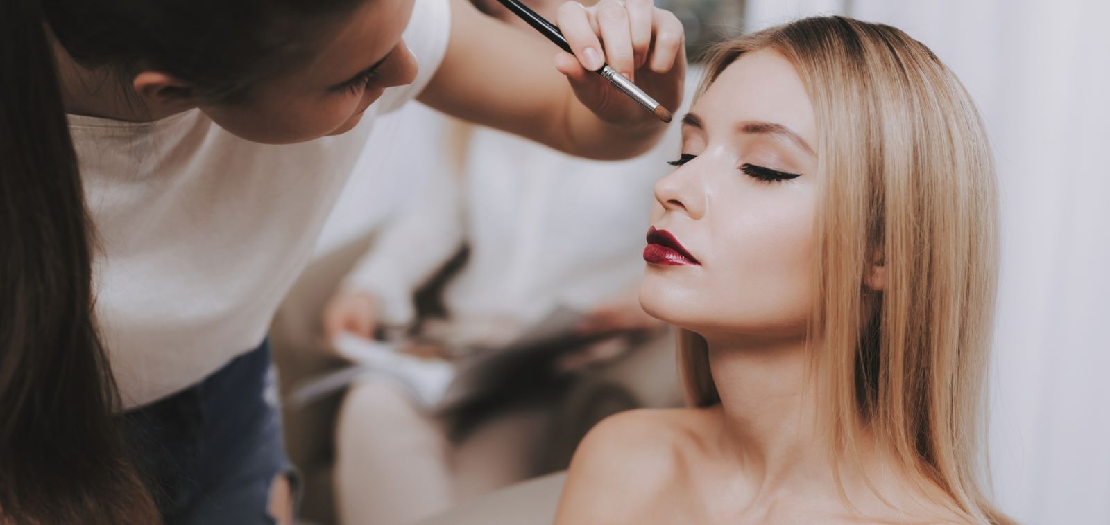 makeup artist adding makeup to a woman