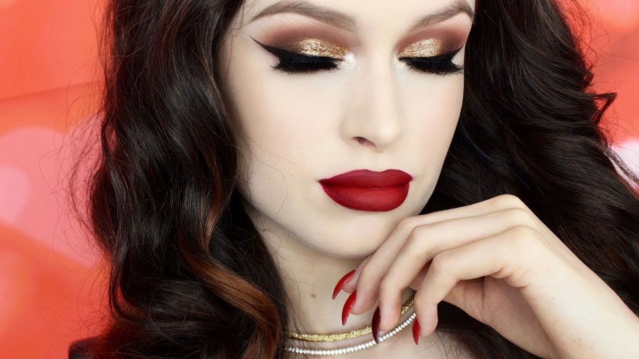 Pale woman with bright red lipstick and gold glitter eyeshadow.